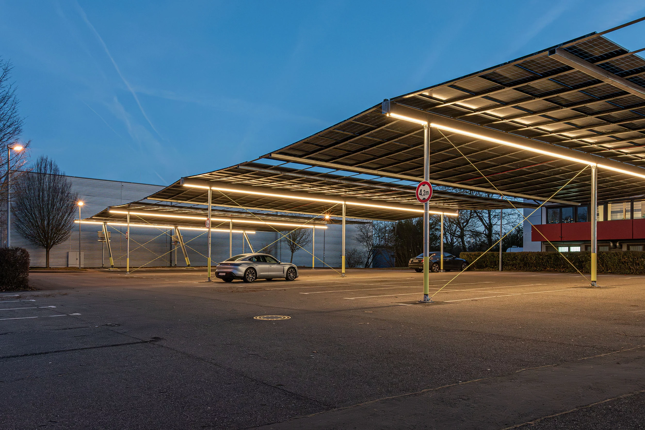Blick auf den beleuchteten Parkplatz unter der Photovoltaikanlage in Hemmingen am Abend, Photovoltaik Parkplatzüberdachung Hemmingen mit Solarmodulen und Blick auf Stellplätze