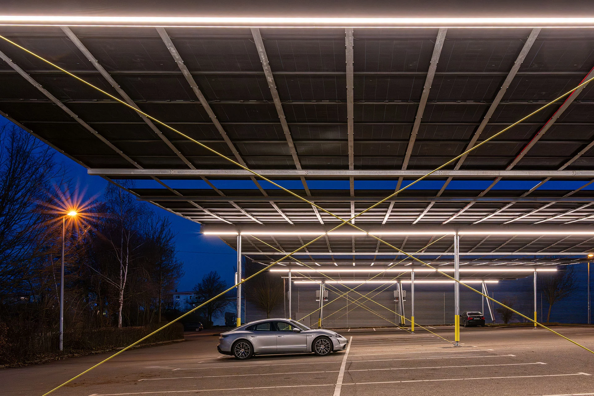 Blick auf den beleuchteten Parkplatz unter der Photovoltaikanlage in Hemmingen am Abend, Photovoltaik Parkplatzüberdachung Hemmingen mit Solarmodulen und Blick auf Stellplätze
