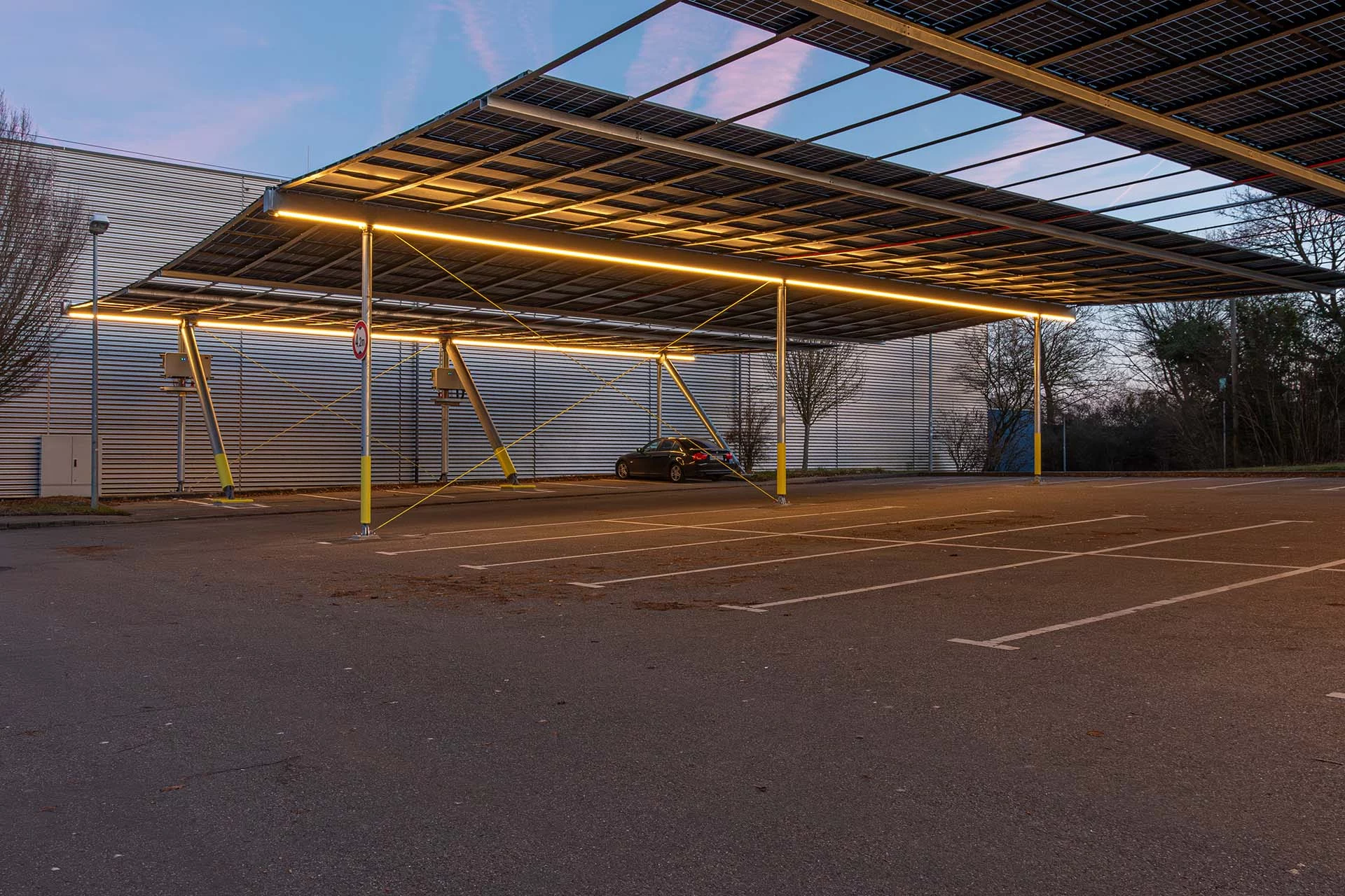 Blick auf den beleuchteten Parkplatz unter der Photovoltaikanlage in Hemmingen am Abend, Photovoltaik Parkplatzüberdachung Hemmingen mit Solarmodulen und Blick auf Stellplätze